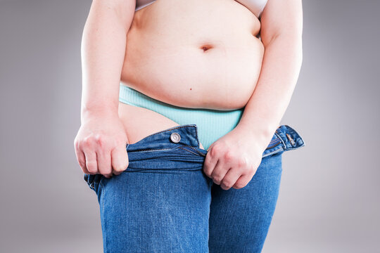 Plus size woman pulling up tight jeans. Overweight, weight loss and body positive concept