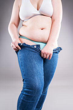 Plus size woman pulling up tight jeans. Overweight, weight loss and body positive concept
