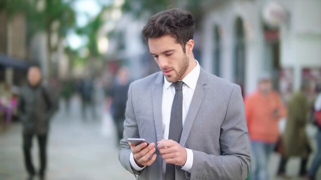 Young Businessman In A Suit Using Smartphone On A Busy City Street, Representing Modern Communication, Mobile Technology, And Professional Lifestyle In An Urban Environment.