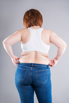 Overweight woman in tight jeans showing love handles and back fat folds, weight loss concept