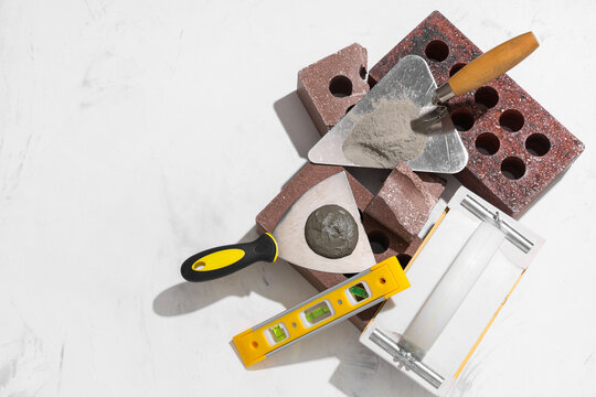 Bricks, plastering float and trowels with cement on white grunge background