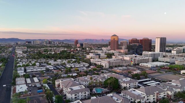 Aerial view of North 7th Street stretching towards the downtown skyline and distant mountains under a sunset sky in Phoenix, Arizona, United States.