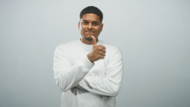 Bearded hispanic man giving thumbs up with right thumb, arms crossed, wearing white long sleeve shirt in studio; approval endorsement.