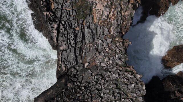 Aerial view of Boca do Inferno - Devil's Mouth with waves crashing against the rugged rocky cliffs and white foam in Cascais, Lisboa, Portugal.