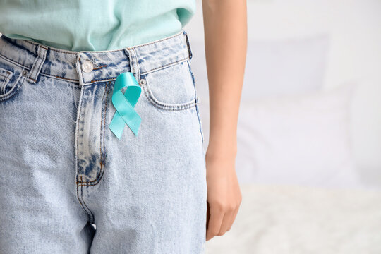 Young woman with turquoise ribbon in bedroom, closeup. Cervical Health Awareness Month