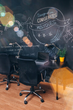 Modern coworking desk with chalkboard wall and laptops