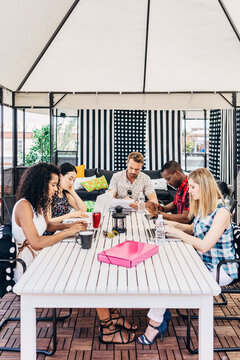 Outdoor team meeting under canopy at patio table
