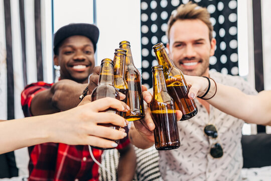 Friends clinking beer bottles at casual indoor party