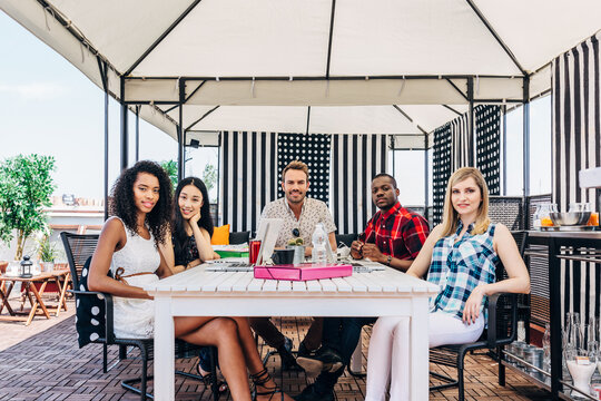 Friends relaxing at outdoor cafe table under canopy