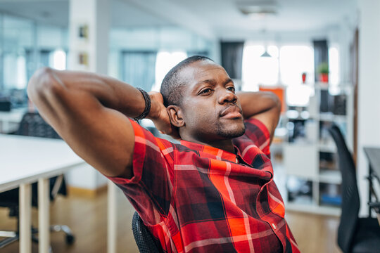 Relaxed black man leaning back in office chair at workplace