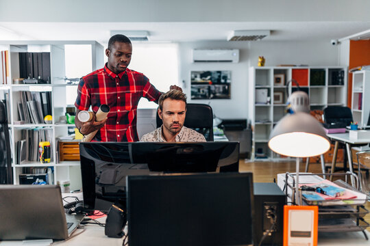 Coworkers collaborating on design project at office desk
