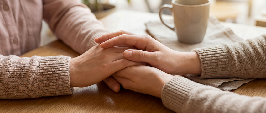support comfort care holding hands empathy warmth cozy home connection clasped hands beside a coffee cup show reassurance empathy and calm connection for counseling wellness and comforting home themes