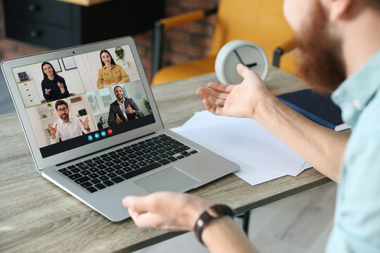 Man having video chat with his coworkers via laptop at home, closeup