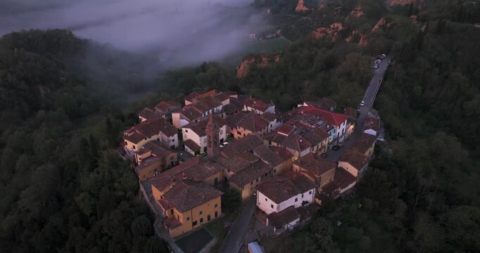 Aerial view of the historic village of Piantravigne with terracotta rooftops and morning mist in the valley Piantravigne, Tuscany, Italy.