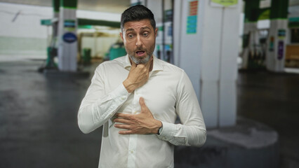 Man clutching throat with one hand and pressing chest for heartattack, white shirt, neck exposed at petrol station building  panic emergency urgent. © Krakenimages.com