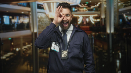 Fototapeta premium Man detective shows badge and id while making an ok circle with his hand over one eye in a building lobby; playful vigilance.