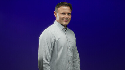 Obraz premium Man smiling handsome hispanic showing thumbs to chest in purple studio with casual shirt; confident warmth approachability.