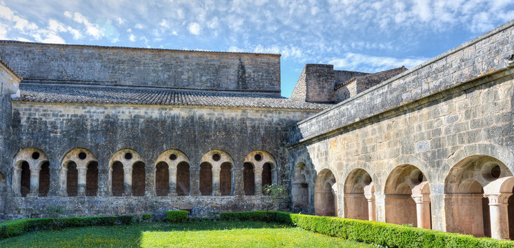 Le Thoronet, Var, France : Romanesque cloister of Abbaye du Thoronet with stone arcades and courtyard garden under soft spring sky in Provence.