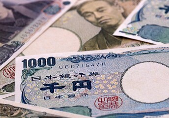 Japanese yen money bills pile on table. Japan banknotes of JPY currency close up. © Larysa