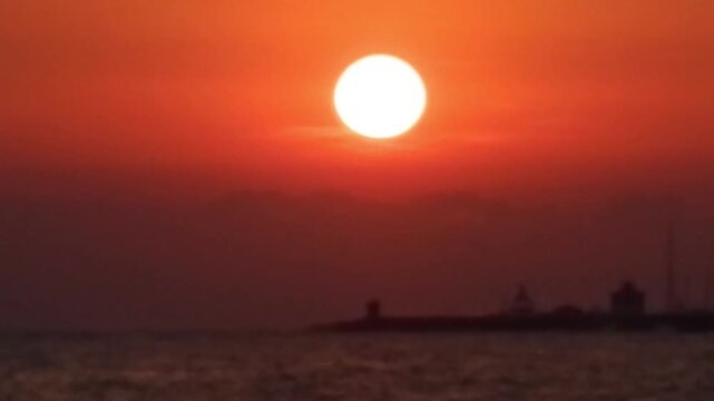 Sunset and red sky with clouds over moving water of sea with small waves and dark horizon of coast - timelapse. Topics: evening, natural seascape, travel, seaside recreation, relaxation, vacation