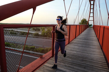 woman with sunglasses running on a bridge