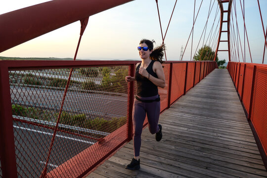 woman with sunglasses running on a bridge
