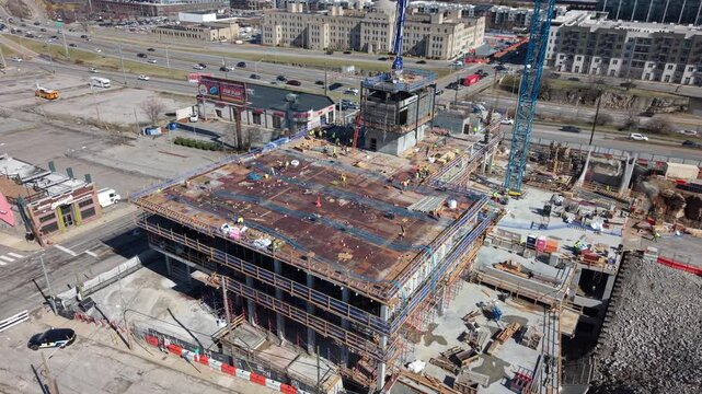 Aerial view of a multi-story building under construction with workers and a crane near a busy highway in Nashville, TN, United States.