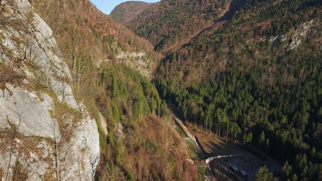 Aerial view of alpine valley and mountains revealed behind limestone cliff