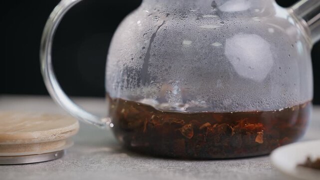 Cascara coffee tea infusion with dried husks in small ceramic bowl and glass teapot for beverage.