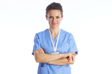 A professional female medical worker in blue scrubs stands with arms crossed, conveying reliability, expertise, and a welcoming approach to healthcare. © Alliance