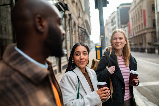 Friends with takeaway coffee chatting on city street
