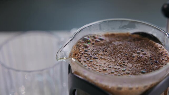 Macro closeup of coffee crema bubbles and texture on french press surface.