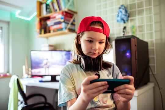 Preteen gamer playing mobile game in bedroom