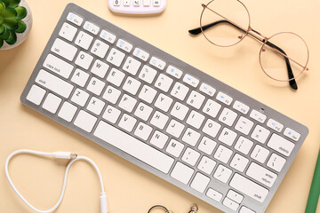 Fototapeta premium Modern office workspace flat lay with wireless keyboard, eyeglasses, cable, calculator and succulent plant on pastel yellow desk, top view minimalist remote work technology background
