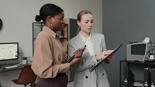 African American businesswomen nodding while reading business documents with her colleague in modern office