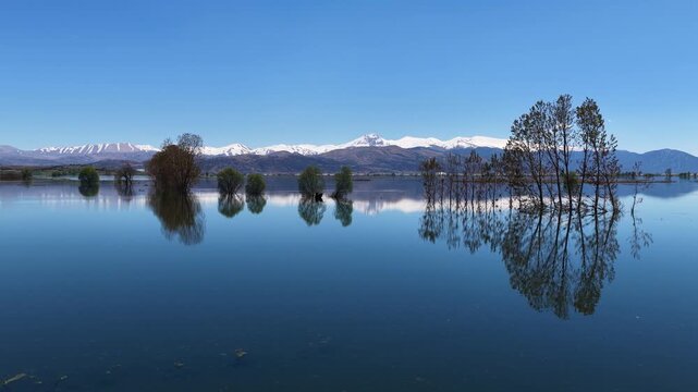 The enchanting reflection of trees and snow-capped mountains in the crystal-clear waters of Elmalı Karag&ouml;l.