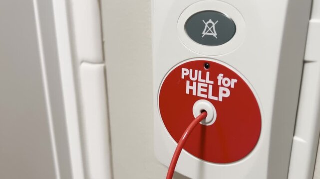 Close up of an emergency help pull button on a wall, safety alert system in an indoor facility.