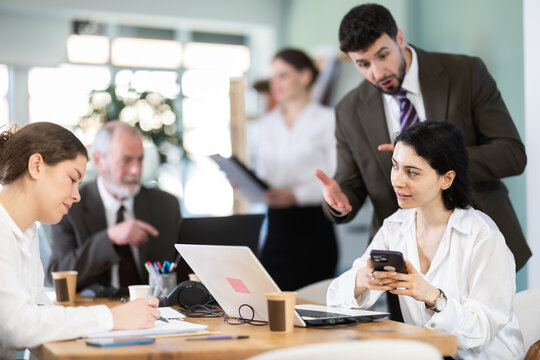 Male boss chastises female subordinate for idleness and scrolling of phone, social networks and stealing personal and working time. Procrastination at work, evading official duties.