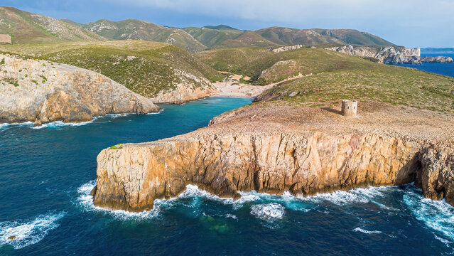 Aerial view of the rugged limestone cliffs and the historic Spanish watchtower at Cala Domestica, Buggerru, Sardinia, Italy