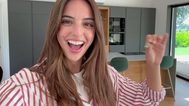 A happy young woman smiles broadly, showcasing the key to her new modern home. Her excitement and joy are evident as she celebrates this significant milestone of homeownership.