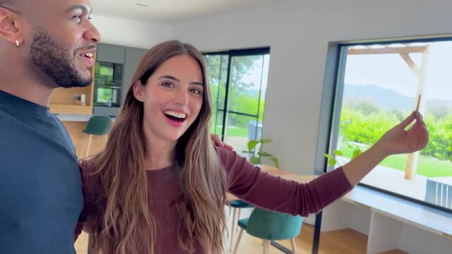 A joyful young couple proudly celebrates a significant milestone, showcasing the key to their beautiful new home. Their palpable excitement marks the beginning of a new chapter of homeownership.
