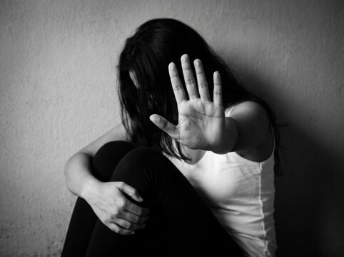 dramatic black and white portrait of woman extending hand in stop gesture with hidden face representing personal safety abuse awareness and emotional protection concept
