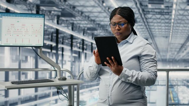 Reviewing schematics, semiconductors and portrait of smiling woman in smart factory. Overseeing layouts, EDA software and cheerful african american businesswoman in industry 4.0 plant, camera B