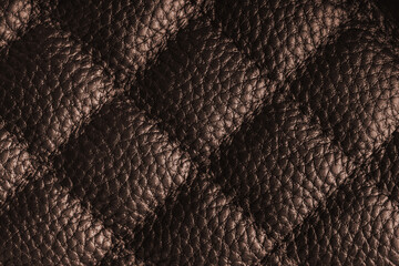 Fototapeta premium Close up, macro of brown quilted leather texture with stitched diamond pattern, luxury material surface shining metal effect for fashion, upholstery or design wallpaper, rough, relief background