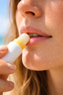 Woman applying lip balm in sunny outdoor environment