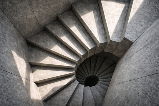 Spiral concrete staircase with shadows and light patterns