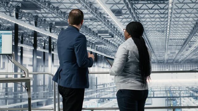 Man and coworker in microchip smart factory developing advanced electronics automation process. Teamworking colleagues using simulation software to optimize semiconductor design flow, camera B