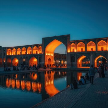 Historic Khaju Bridge illuminated at dusk with reflections in the Zayandeh River.