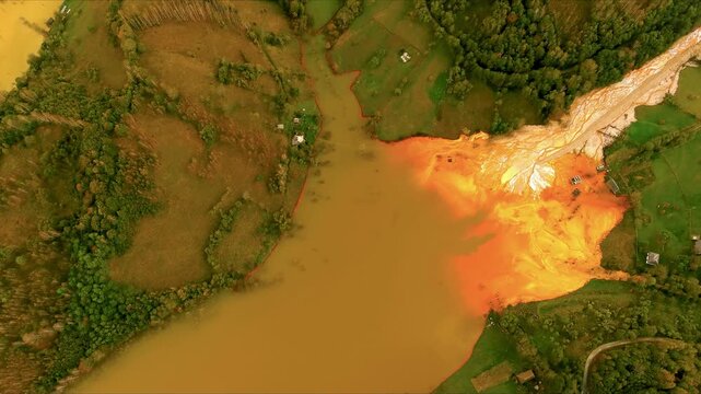 Aerial view of the toxic tailings pond with orange polluted water and flooded landscape in Geamana, Alba County, Romania.