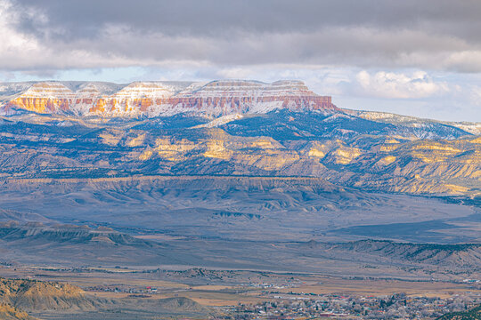 Wide landscape showing snow-dusted layered mesas and plateaus overlooking the vast arid valley near Bryce Canyon National Park.